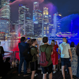 Cruzeiro no rio ao pôr do sol em Singapura e espectáculos de luzes cintilantes