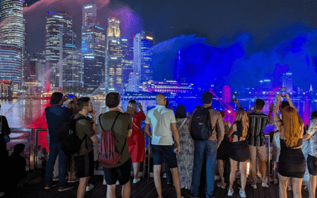 Cruzeiro no rio ao pôr do sol em Singapura e espectáculos de luzes cintilantes