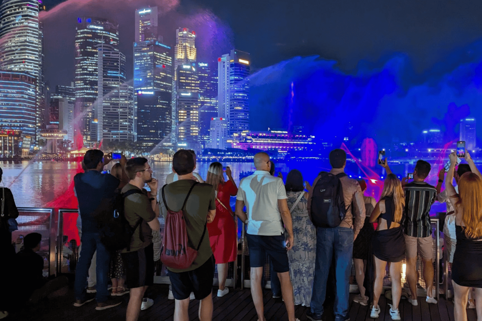 Cruzeiro no rio ao pôr do sol em Singapura e espectáculos de luzes cintilantes